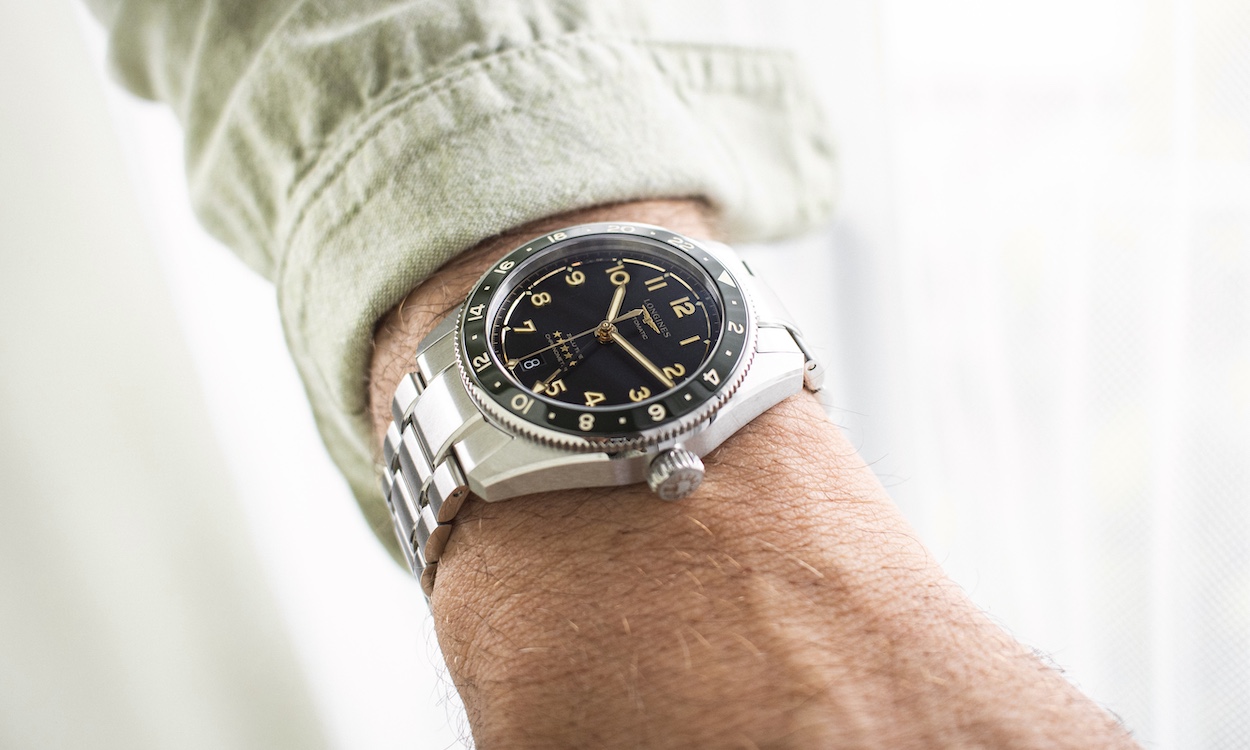 Longines Spirit Zulu Time 39 am Handgelenk eines Mannes mit grünem Hemd in Nahaufnahme.