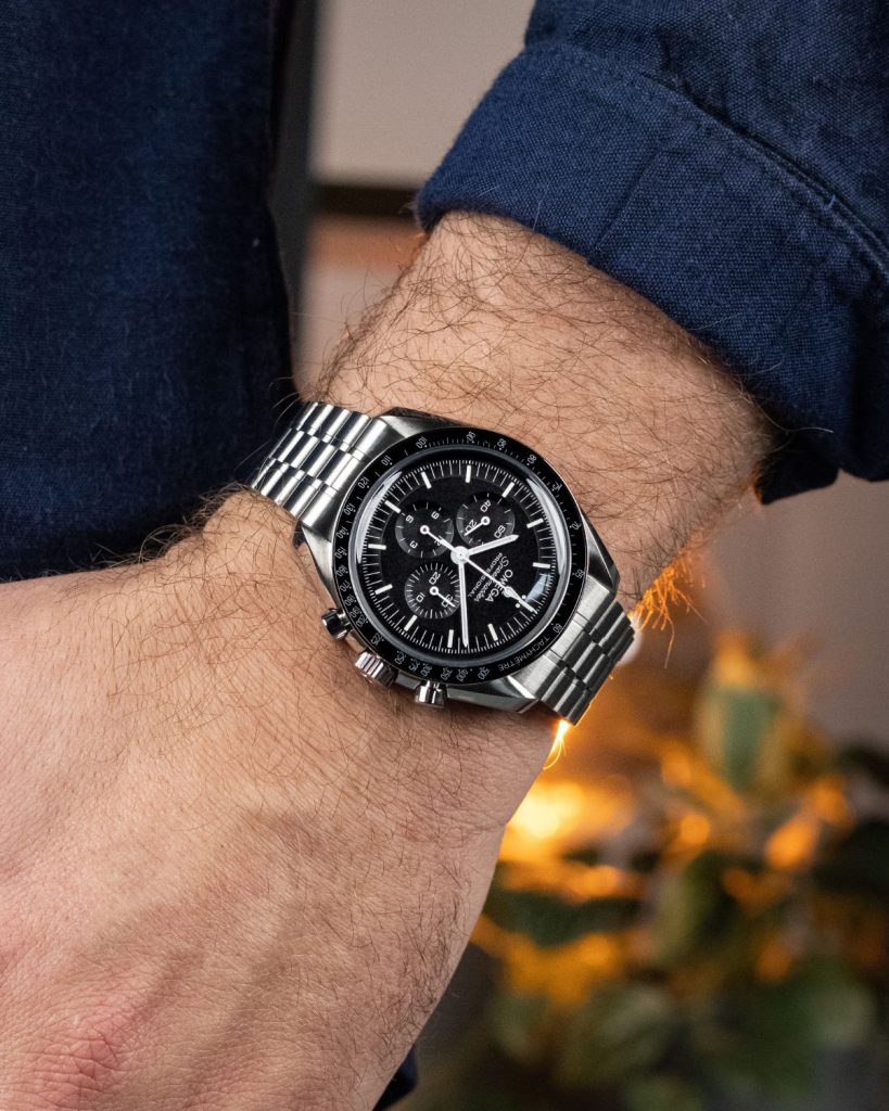 OMEGA Speedmaster Moonwatch Referenz 310.30.42.50.01.002 mit schwarzem Zifferblatt am Edelstahlarmband an einem Handgelenk getragen