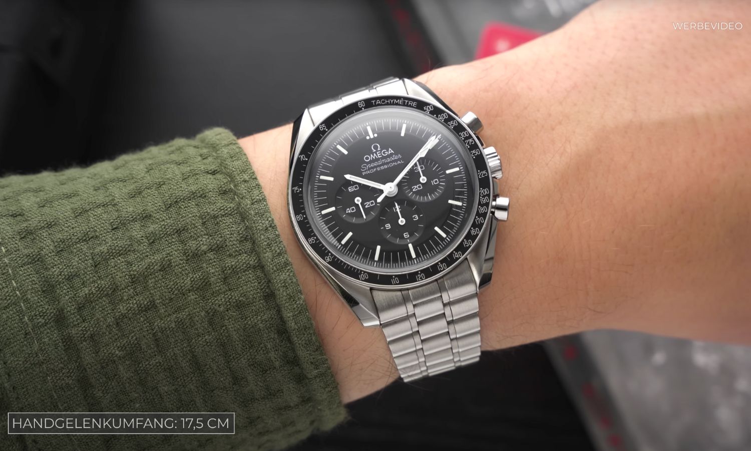OMEGA Speedmaster Professional Moonwatch Hesalit Referenz 310.30.42.50.01.001 mit schwarzem Zifferblatt am Edelstahlarmband an einem Handgelenk mit grünem Ärmel getragen