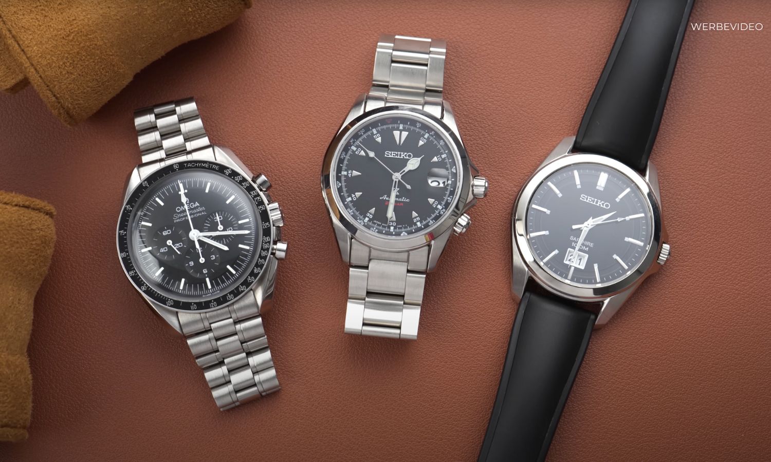 OMEGA Speedmaster Professional Moonwatch Hesalit Referenz 310.30.42.50.01.001 links, Seiko Alpinist SPB117 in der Mitte und Seiko Quarz Big Date Referenz SUR009P1 rechts nebeneinander liegend vor hellbraunem Hintergrund