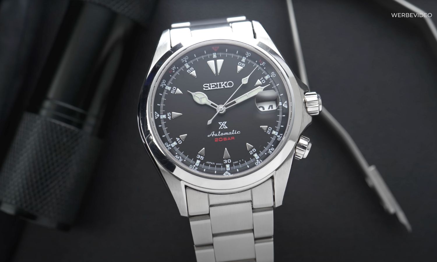 Seiko Alpinist SPB117 mit schwarzem Zifferblatt am Edelstahlarmband stehend vor schwarzem Hintergrund