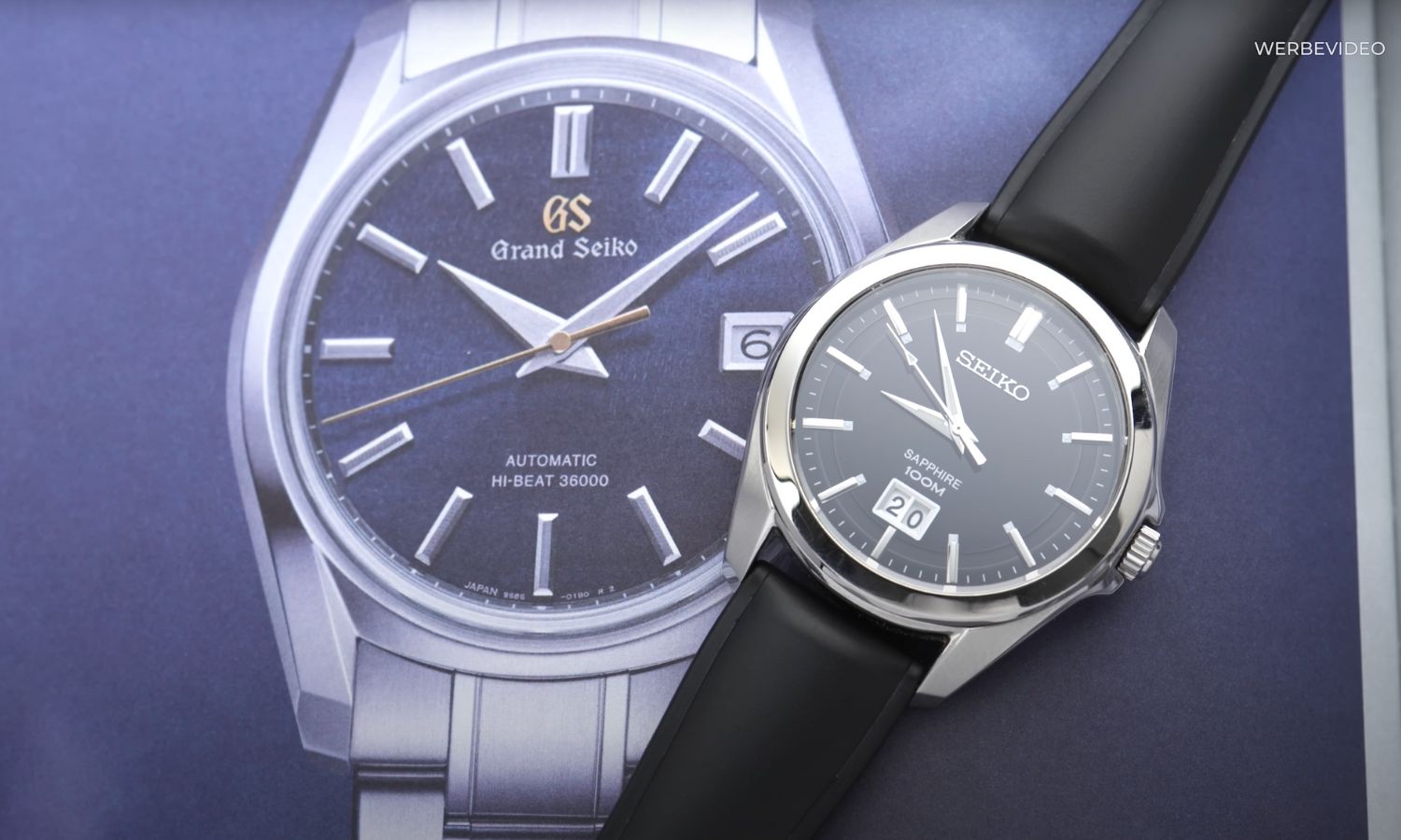 Seiko Quarz Big Date Referenz SUR009P1 mit schwarzem Zifferblatt am schwarzen Lederarmband liegend auf einem Hintergrund mit einer abgebildeten Grand Seiko