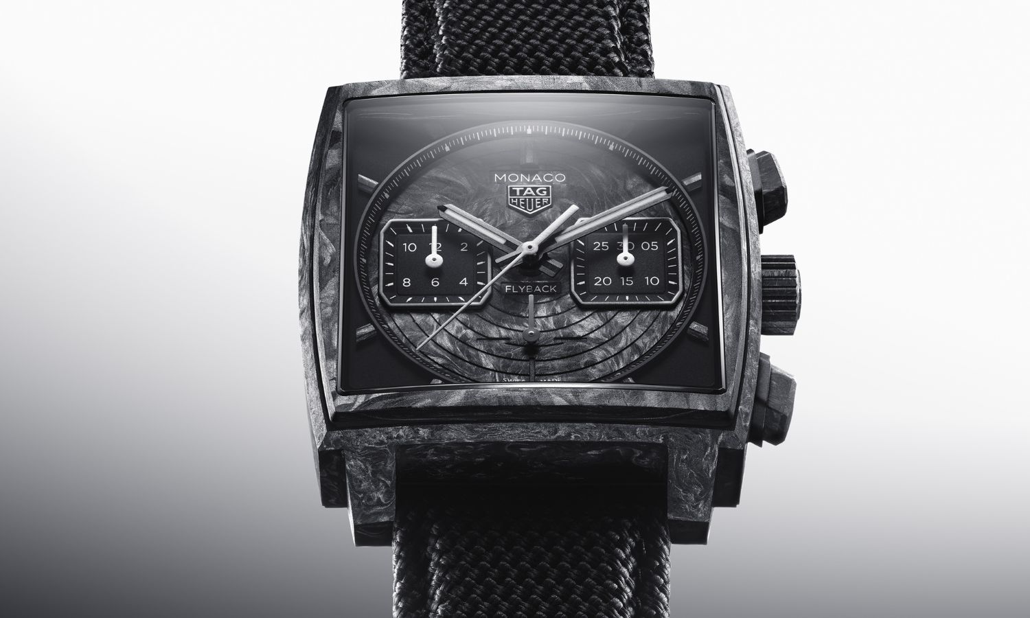 TAG HEUER Monaco Flyback Chronograph TH-Carbonspring Referenz CBL5190.FT6313 mit schwarzem Zifferblatt und schwarzem Carbongehäuse von vorne abgebildet vor grau-weißem Hintergrund