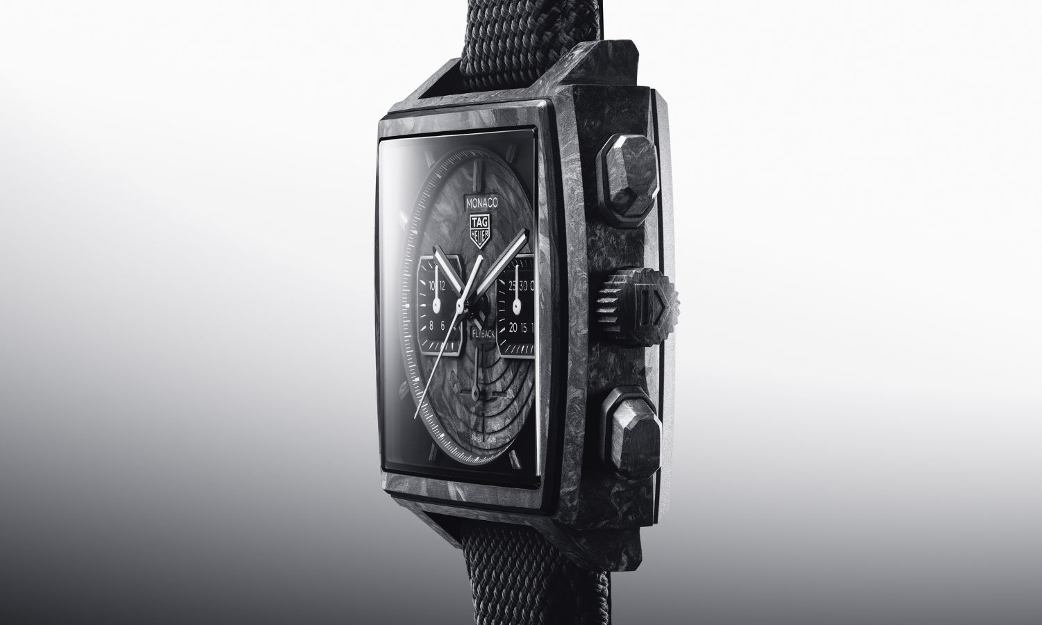 TAG HEUER Monaco Flyback Chronograph TH-Carbonspring Referenz CBL5190.FT6313 mit schwarzem Zifferblatt und schwarzem Carbongehäuse seitlich abgebildet vor grau-weißem Hintergrund