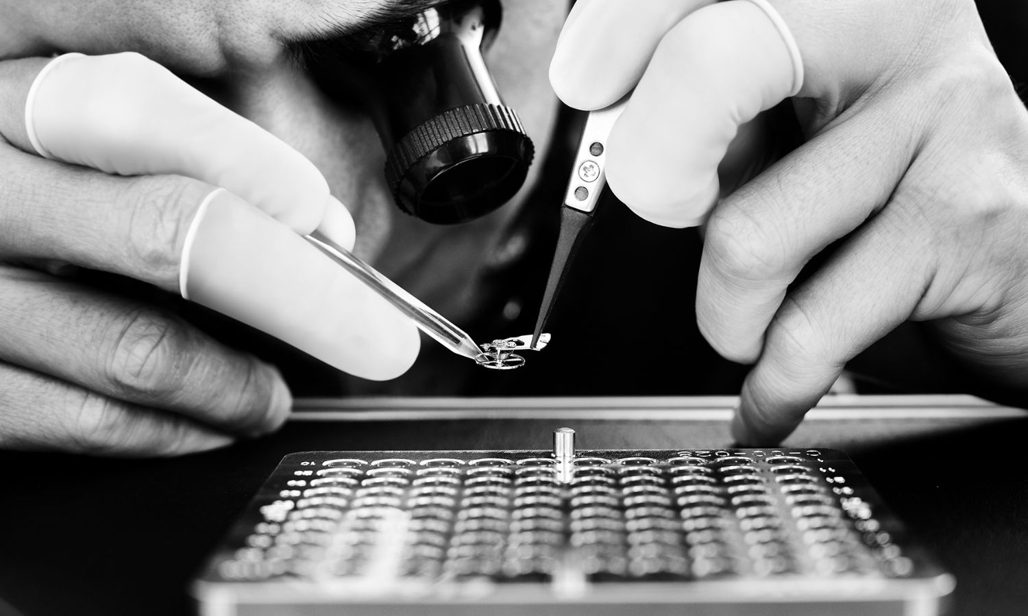 TAG HEUER TH-Carbonspring in einer Pinzette gehalten vor schwarzem Hintergrund