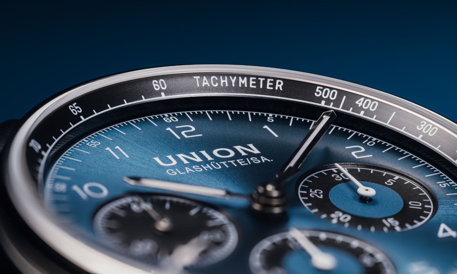 Nahaufnahme des blauen Zifferblatts der UNION Glashütte Belisar Chronograph Referenz D009.227.16.042.00 abgebildet vor blauem Hintergrund