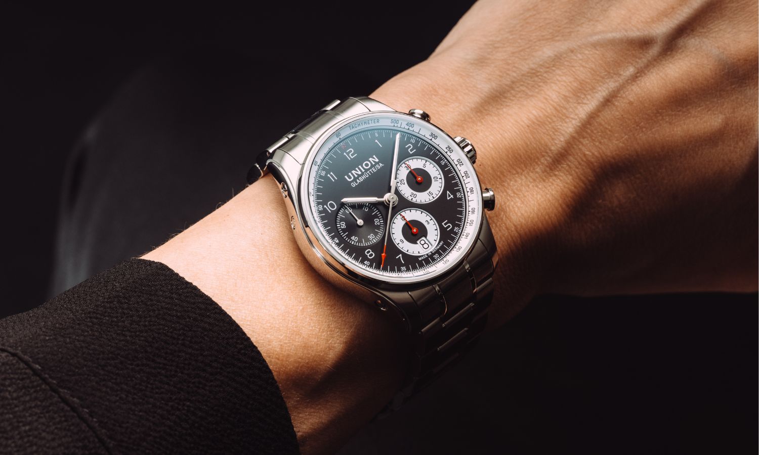 UNION Glashütte Belisar Chronograph Referenz D009.227.11.052.00 mit schwarzem Zifferblatt am Edelstahlarmband an einem Handgelenk mit schwarzem Hintergrund