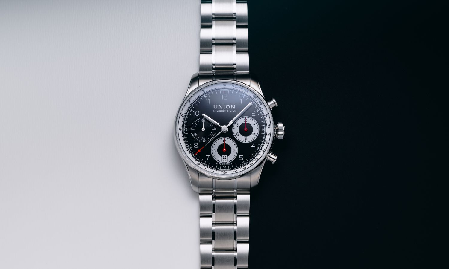 UNION Glashütte Belisar Chronograph Referenz D009.227.11.052.00 mit schwarzem Zifferblatt am Edelstahlarmband liegend vor weiß schwarzem Hintergrund