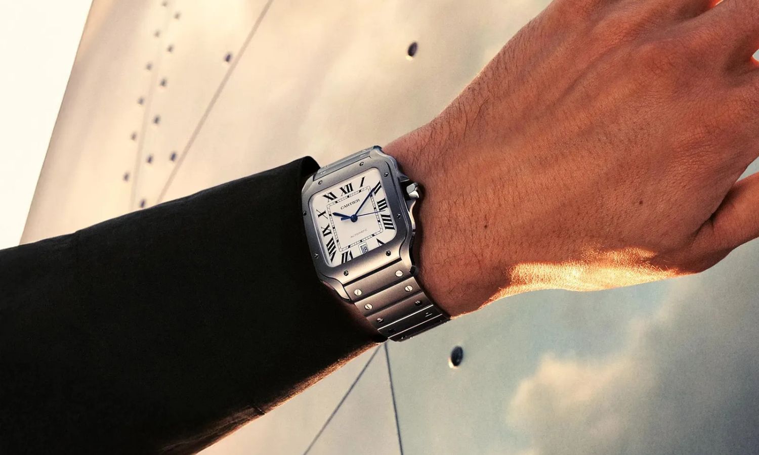 Cartier Santos Referenz WSSA0089 mit Titangehäuse, Titanarmband und weißem Zifferblatt an einem Handgelenk mit schwarzem Ärmel getragen