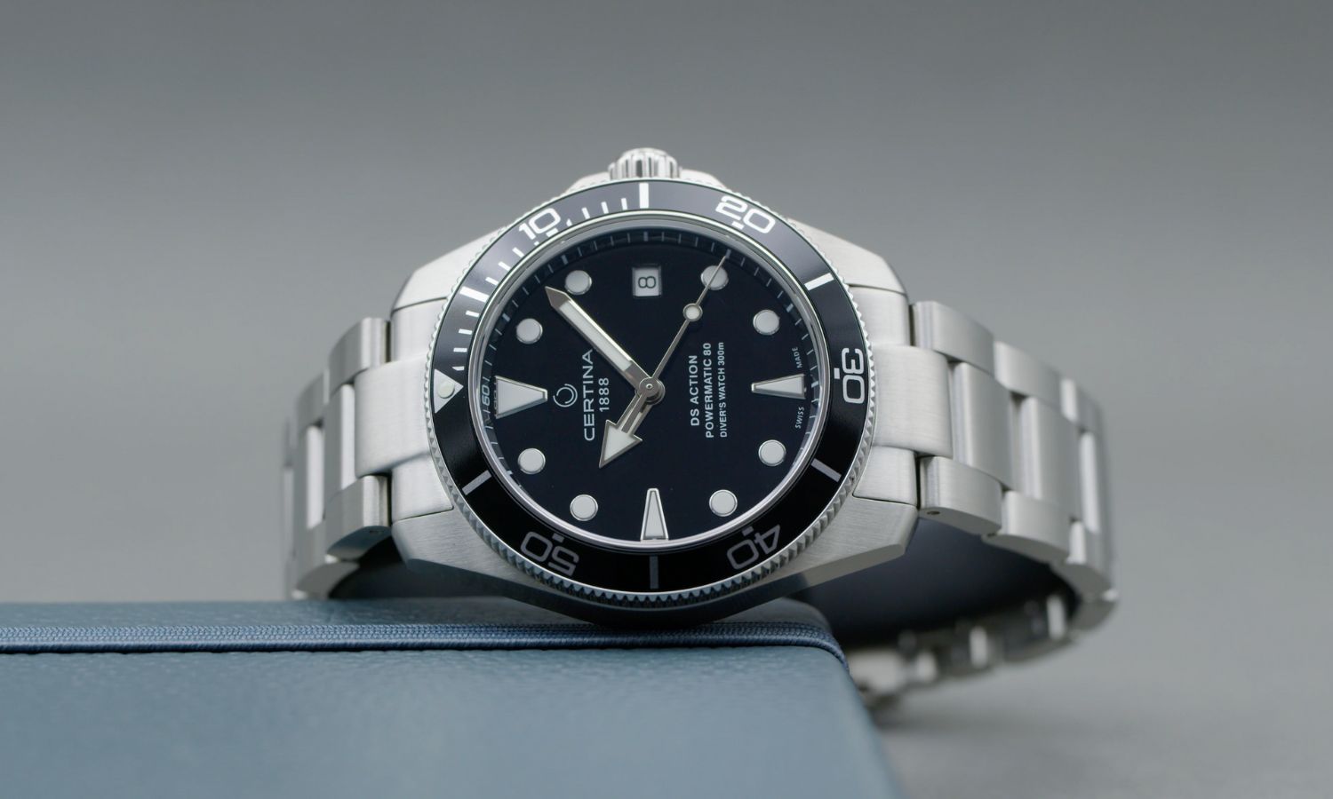 Certina DS Action Diver 38mm mit schwarzem Zifferblatt am Edelstahlarmband seitlich liegend vor grauem Hintergrund