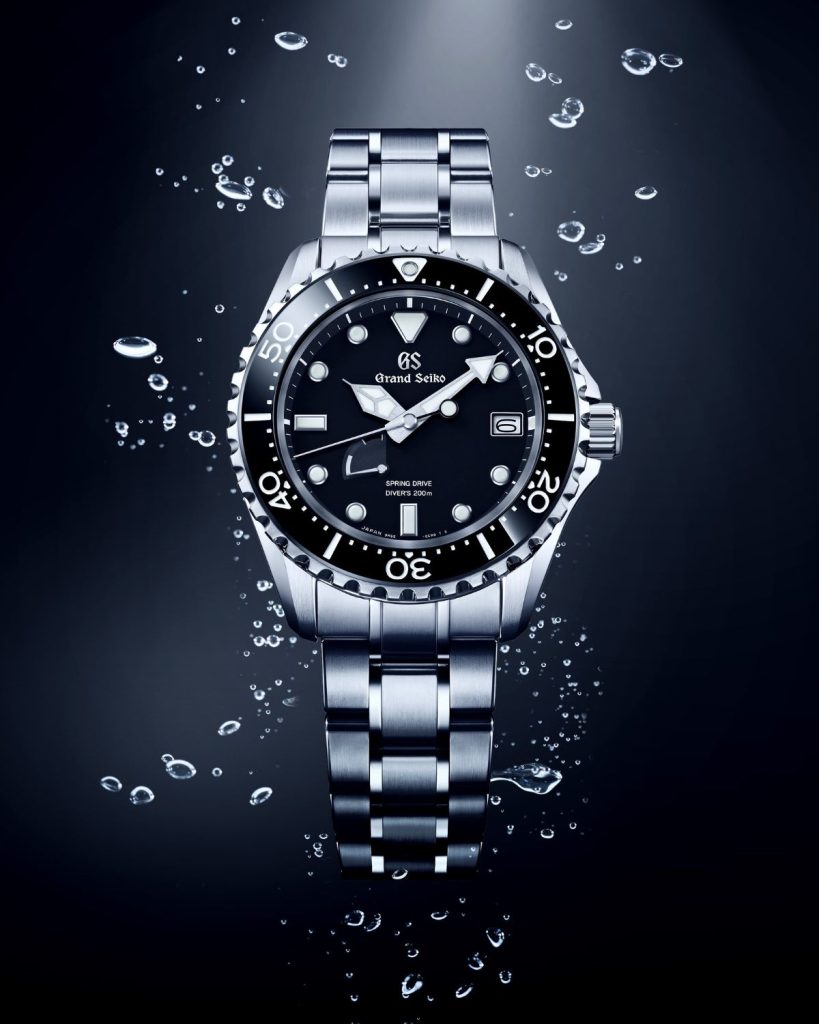 Grand Seiko Sport Spring Drive SBGA461 mit schwarzem Zifferblatt am Edelstahlarmband unter Wasser abgebildet mit Luftbläschen um die Uhr herum vor dunklem Hintergrund