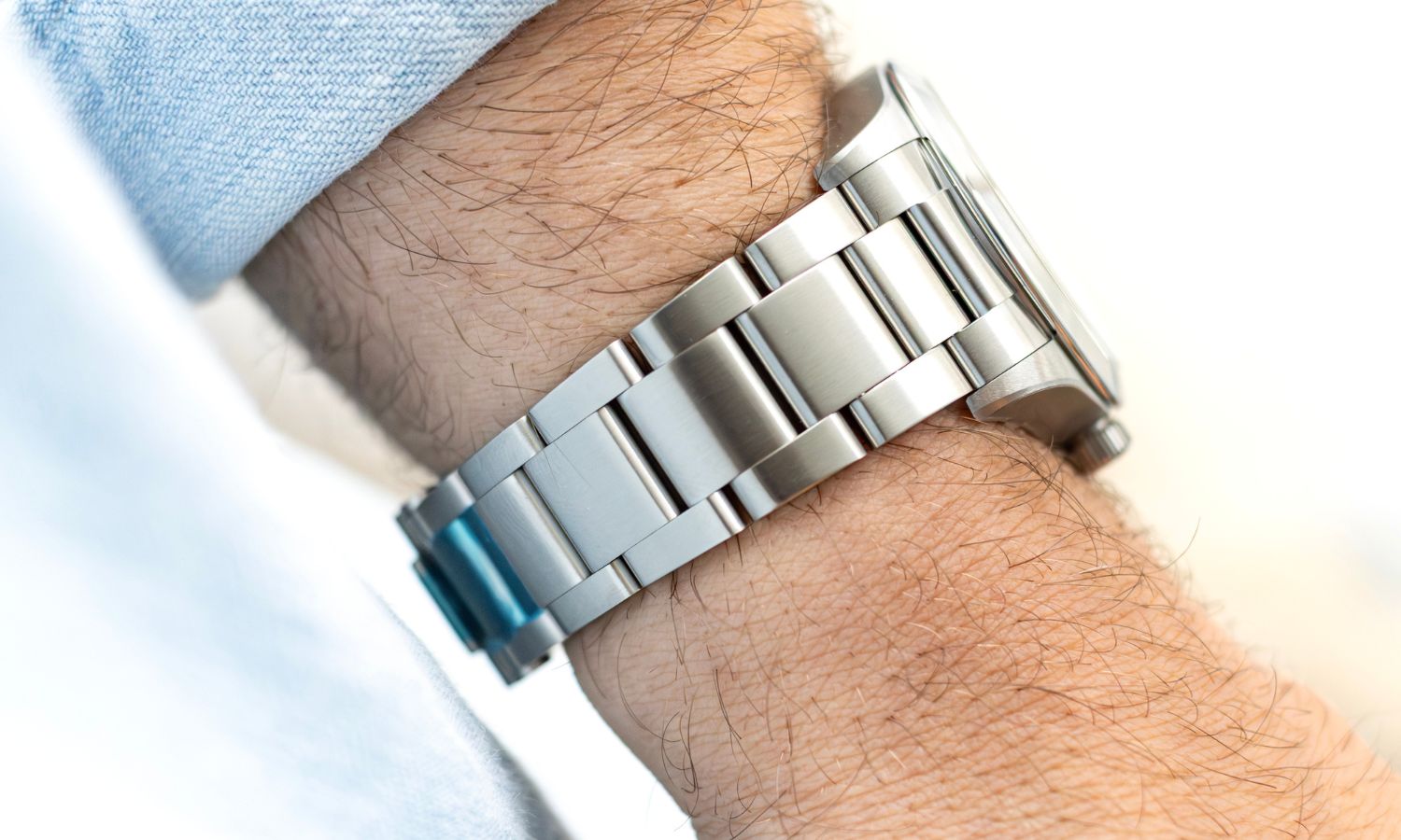 Das Edelstahlarmband der TUDOR Ranger „Dune White“ an einem Handgelenk mit hellblauem Ärmel getragen