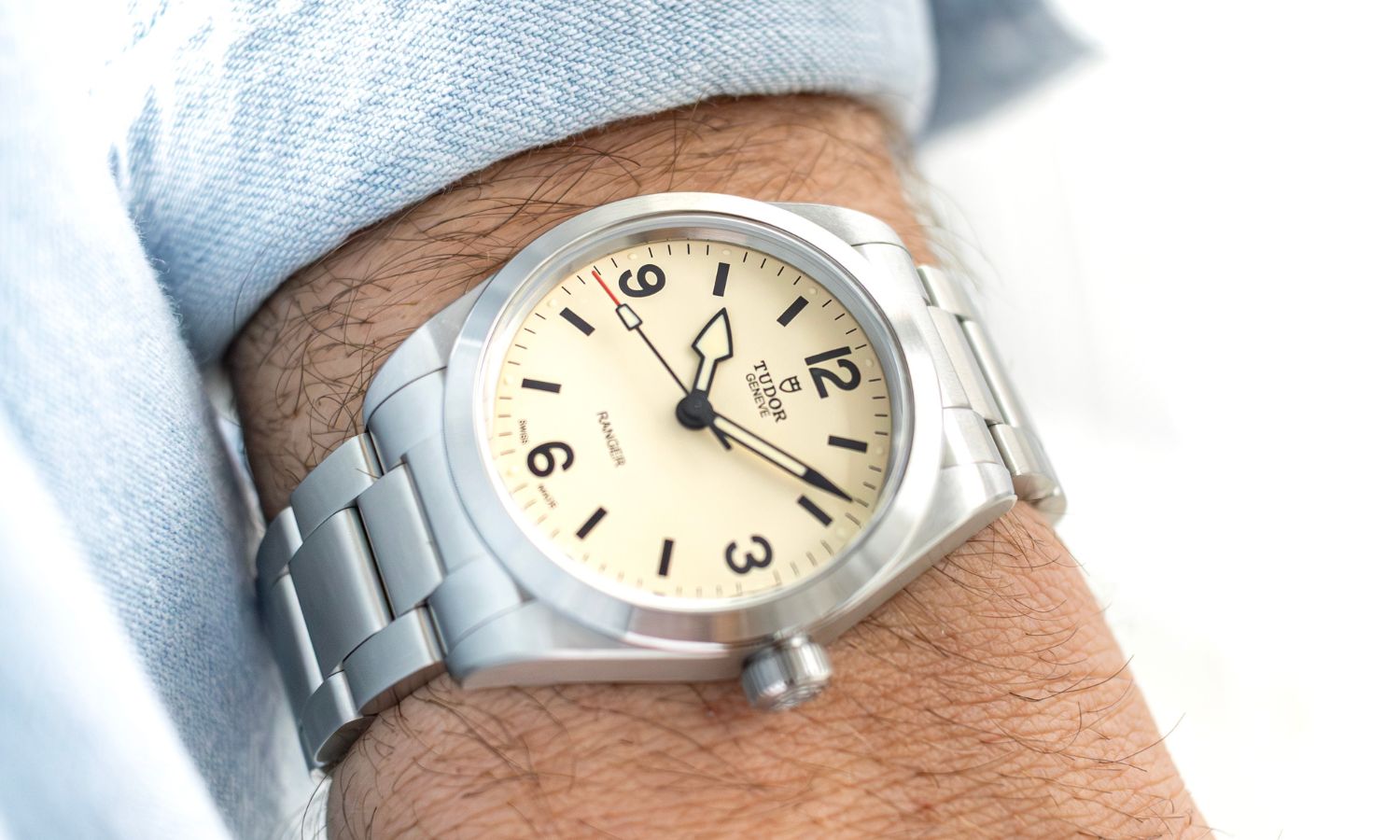 TUDOR Ranger „Dune White“ mit cremeweißem Zifferblatt am Edelstahlarmband an einem Handgelenk mit hellblauem Ärmel getragen