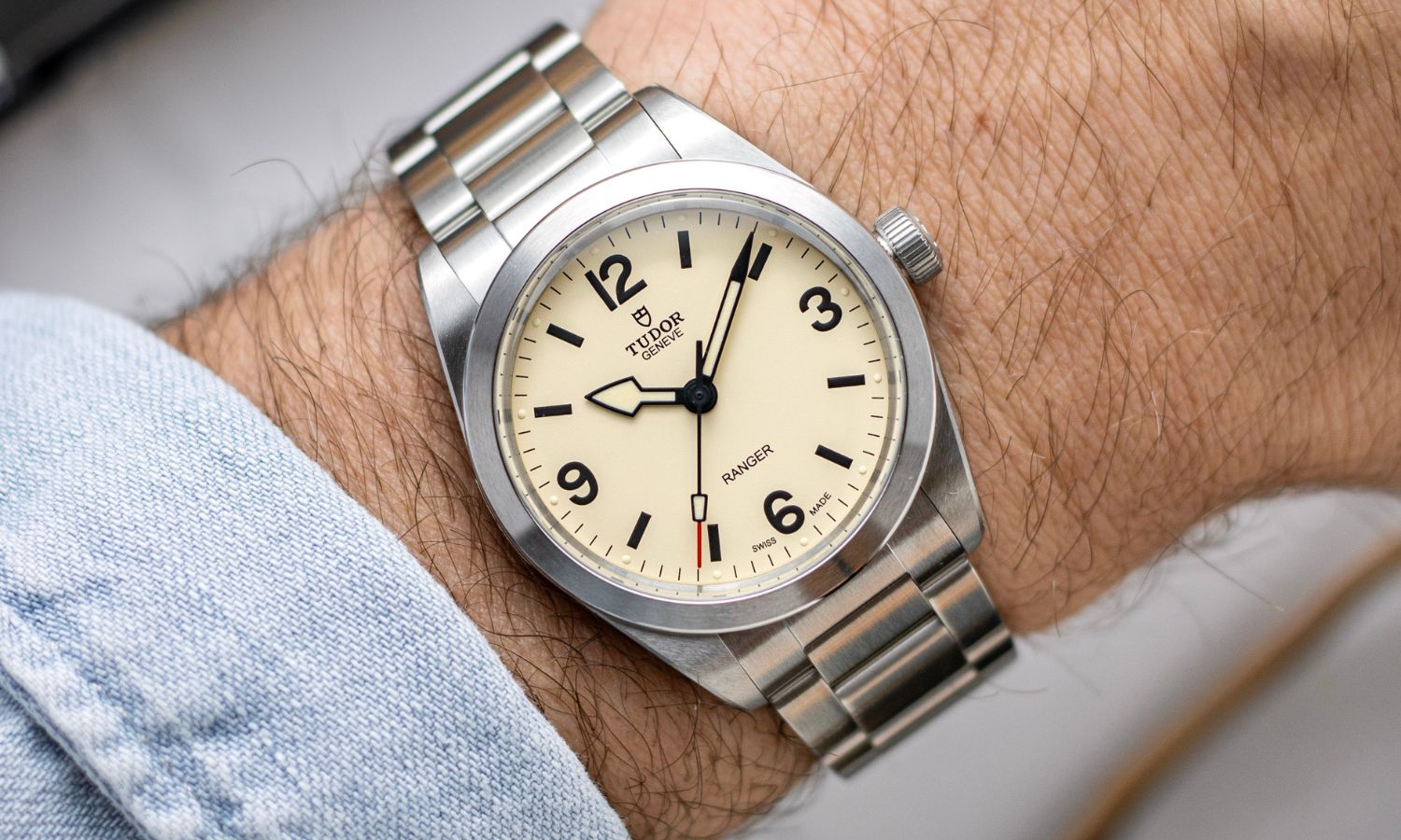 TUDOR Ranger „Dune White“ mit cremeweißem Zifferblatt am Edelstahlarmband an einem Handgelenk mit hellblauem Ärmel getragen