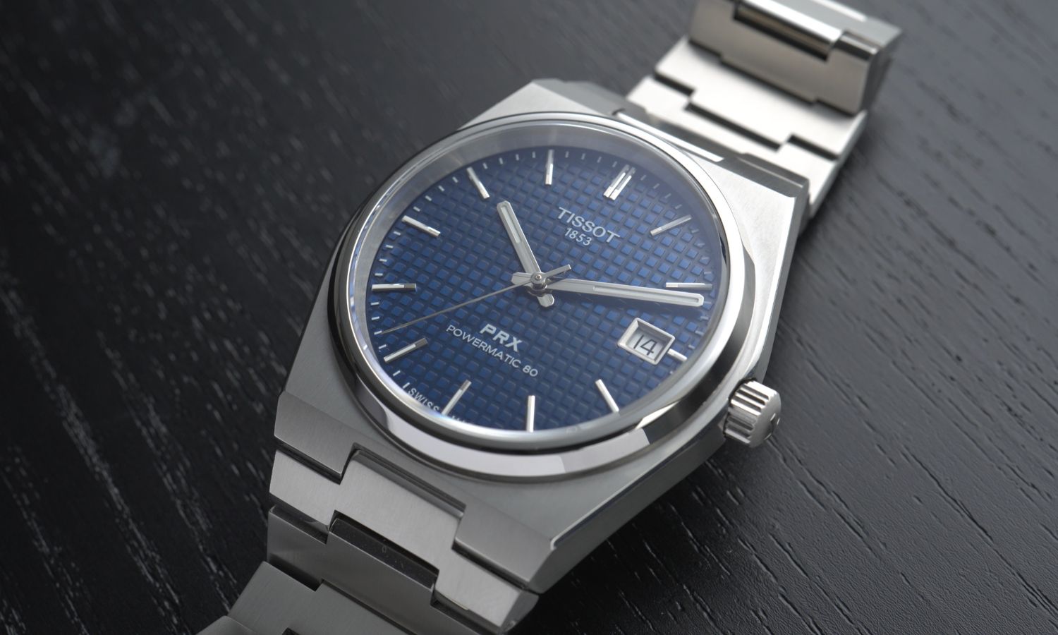 Tissot PRX Powermatic 80 Titan 38 mm Referenz T137.807.44.041.00 mit blauem Zifferblatt am Titanarmband von vorne abgebildet liegend vor schwarzem Hintergrund