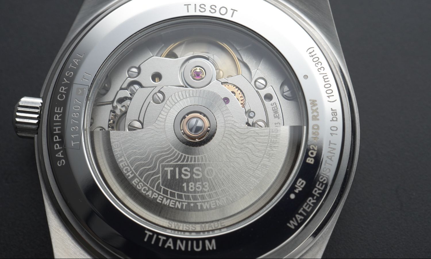 Nahaufnahme des Tissot PRX Powermatic 80 Uhrwerks abgebildet vor schwarzem Hintergrund