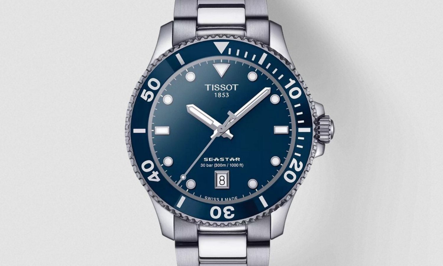 Tissot Seastar 1000 mit blauem Zifferblatt am Edelstahlarmband von vorne abgebildet vor hellgrauem Hintergrund