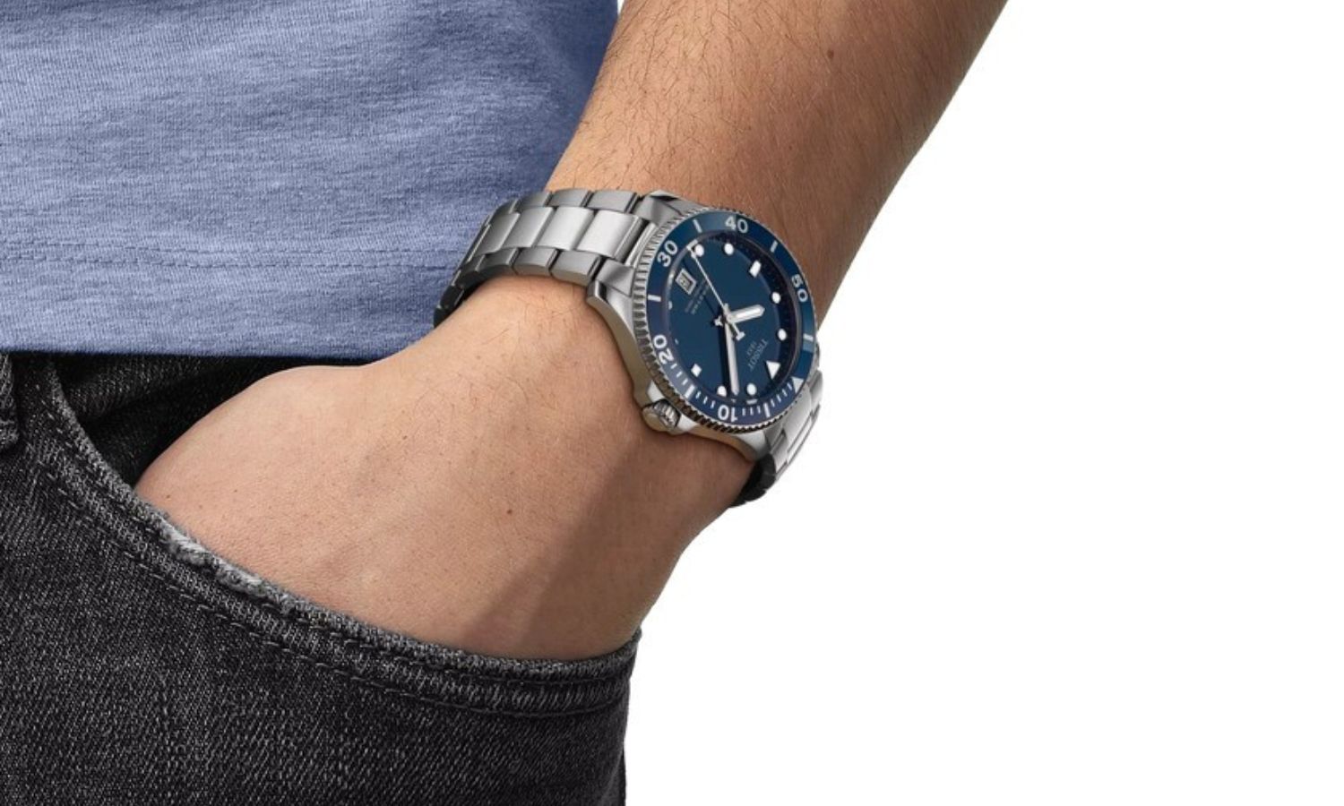Tissot Seastar 1000 mit blauem Zifferblatt am Edelstahlarmband an einem Handgelenk getragen vor weißem Hintergrund