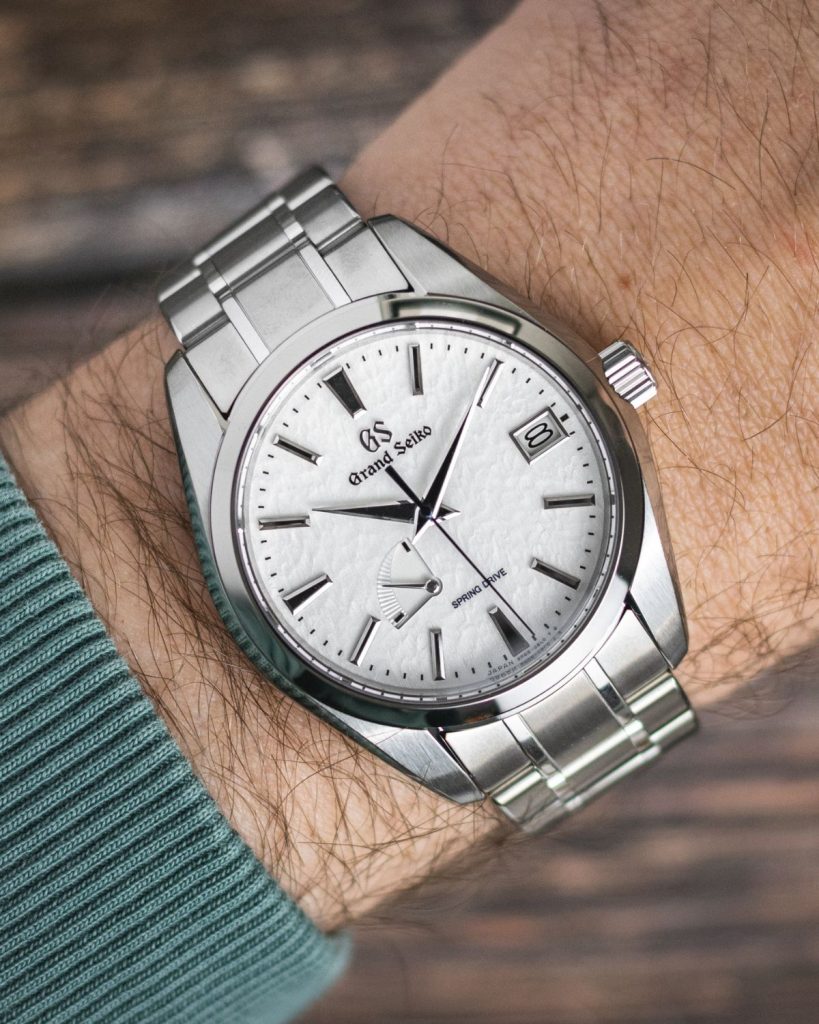 Grand Seiko Snowflake SBGA211 getragen am linken Handgelenk mit grünem Pullover