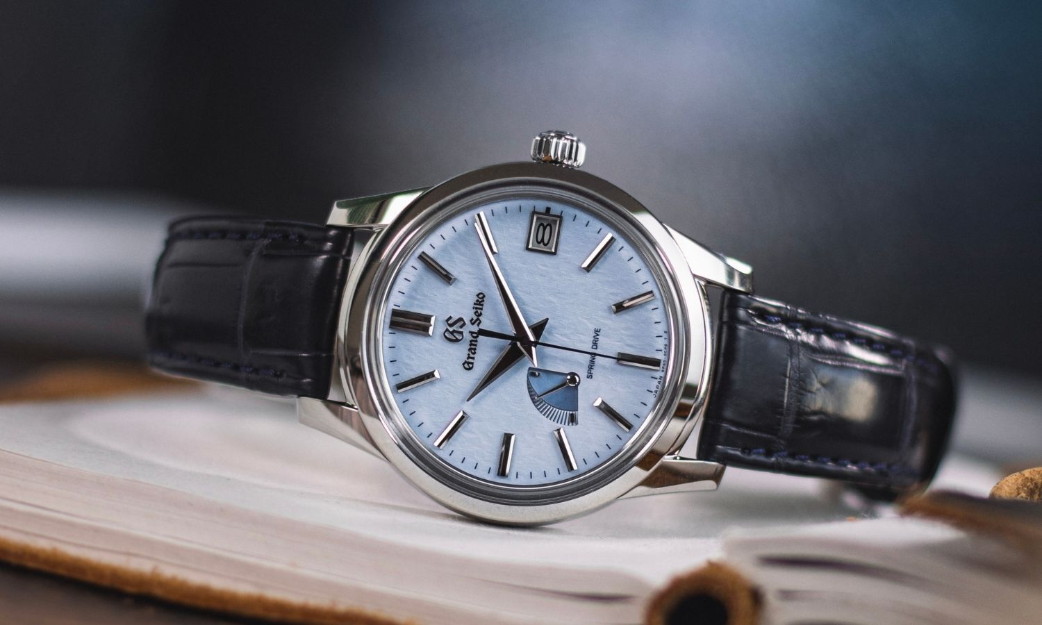 Grand Seiko Snowflake SBGA407 am schwarzen Lederband auf einem offenen Buch liegend