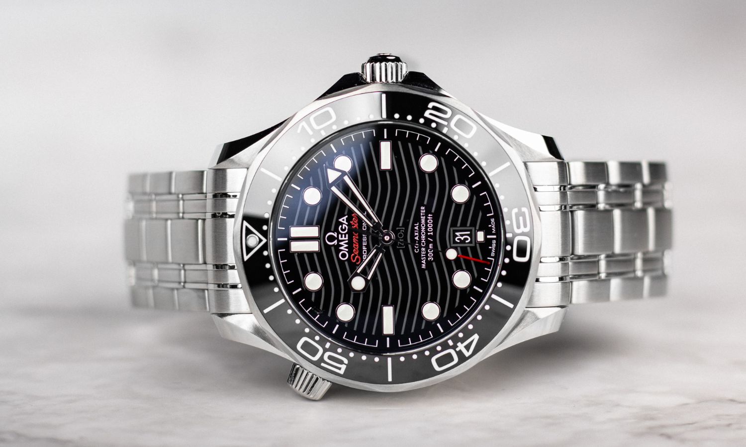 OMEGA Seamaster Diver 300M Referenz 210.30.42.20.01.001 mit schwarzem Zifferblatt am Edelstahlarmband seitlich liegend vor hellem Hintergrund