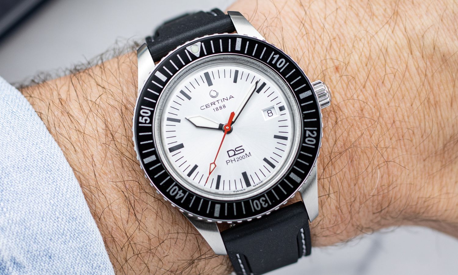Certina DS PH200M Powermatic 80 mit silbernem Zifferblatt an einem Handgelenk getragen mit hellblauem Ärmel abgebildet vor hellem Hintergrund
