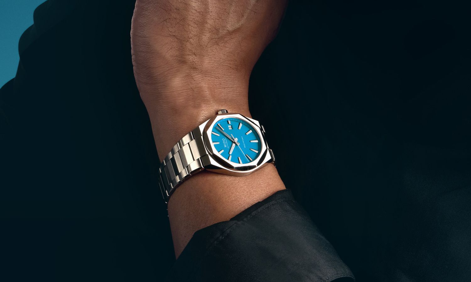 Mido Multifort 8 One Crown Referenz M055.507.11.041.00 mit blauem Zifferblatt am Edelstahlarmband an einem Handgelenk getragen abgebildet vor schwarzem Hintergrund