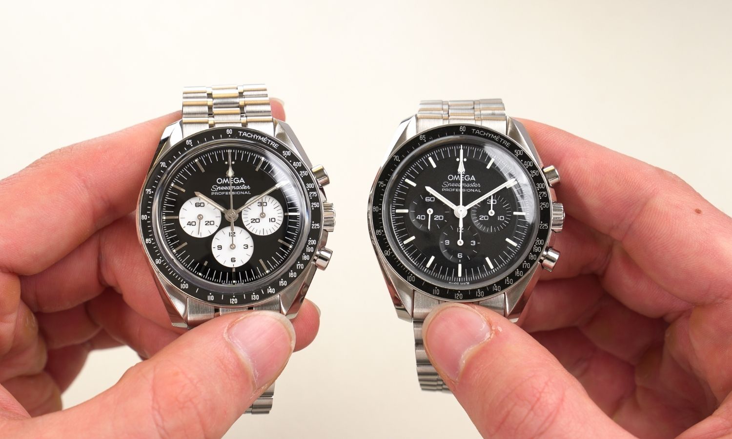 OMEGA Speedmaster Moonwatch Professional Hesalit und OMEGA Speedmaster Moonwatch Professional „Reverse Panda“ Referenz 310.30.42.50.01.004 mit schwarzem Zifferblatt am Edelstahlarmband nebeneinander in zwei Händen gehalten