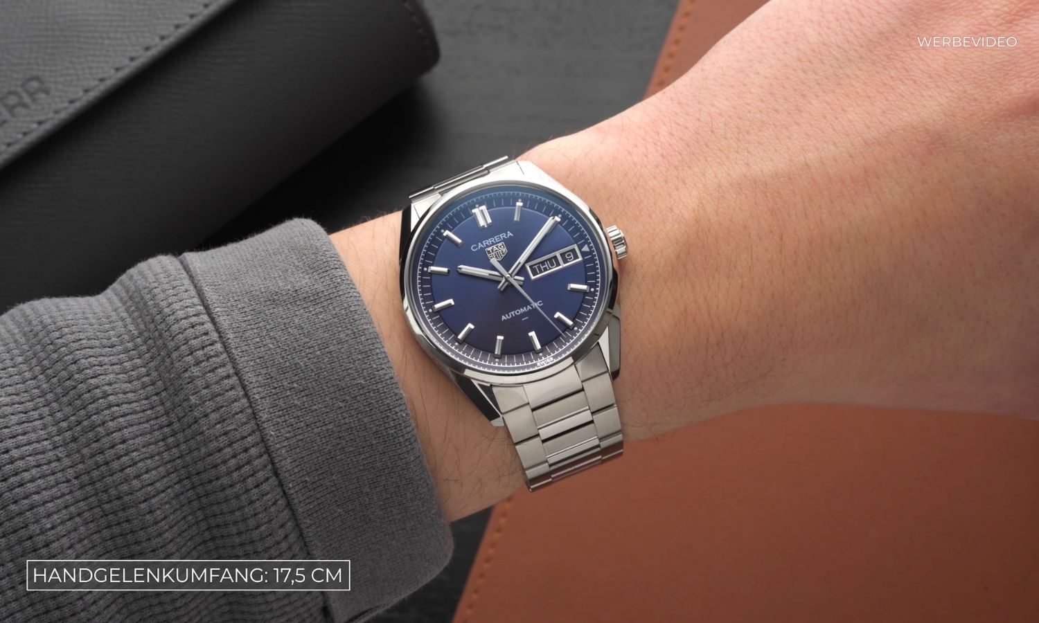 TAG HEUER Carrera Day-Date mit blauem Zifferblatt am Edelstahlarmband an einem Handgelenk mit grauem Zifferblatt getragen