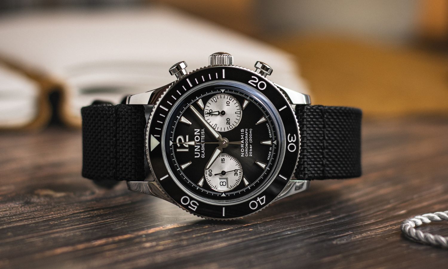 UNION Glashütte Noramis Chronograph Sport mit schwarzem Zifferblatt am schwarzen Textilarmband auf der Seite liegend auf hölzernem Untergrund