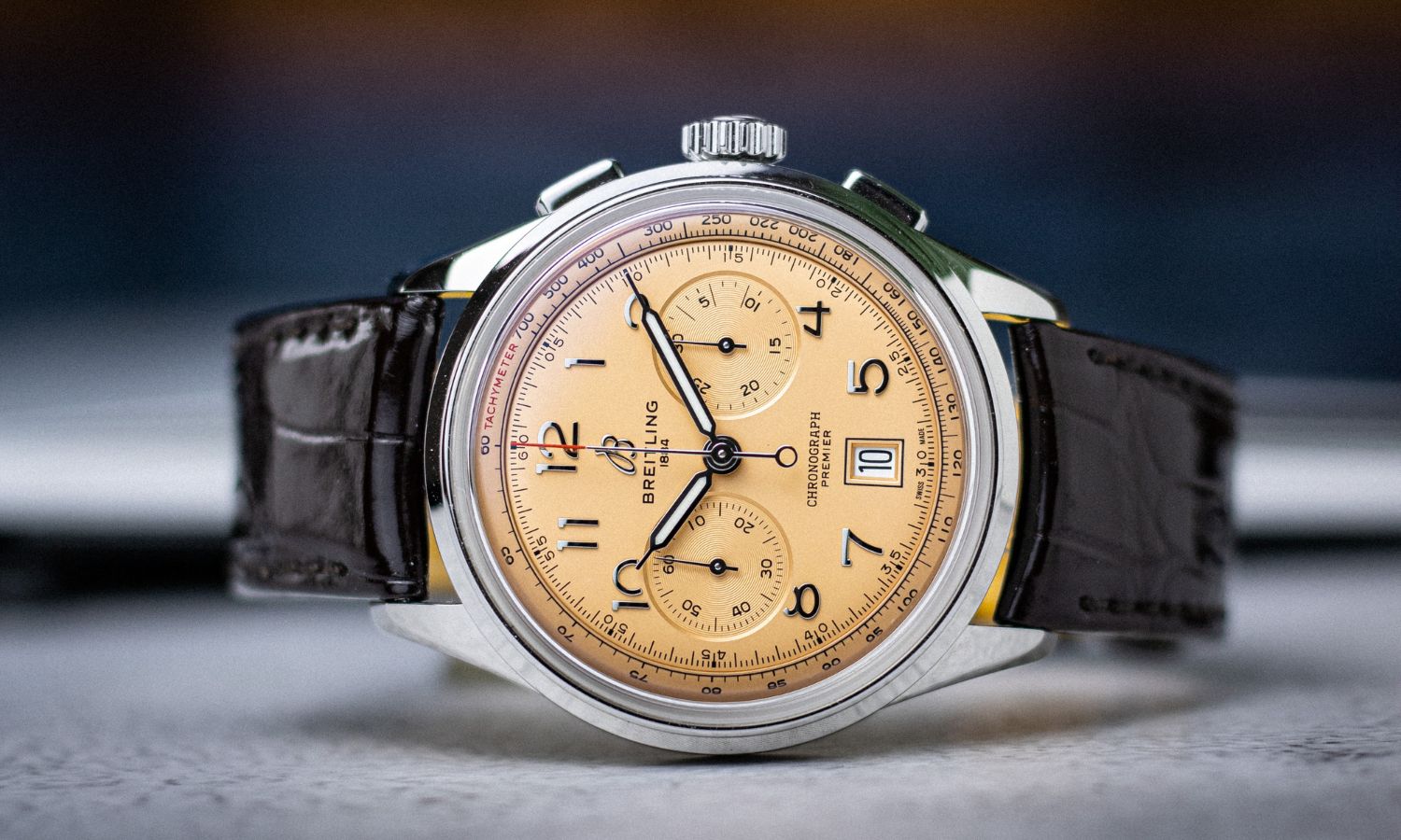 Breitling Premier B01 Chronograph 42 mit lachsfarbenem Zifferblatt am schwarzen Lederarmband seitlich liegend