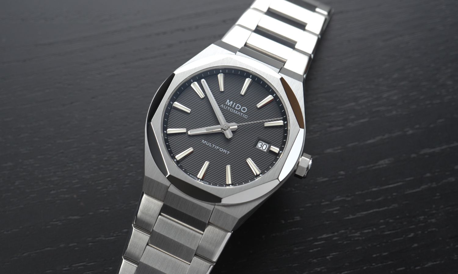 Mido Multifort 8 One Crown Referenz M055.507.11.051.00 mit schwarzem Zifferblatt am Edelstahlband liegend vor schwarzem Hintergrund