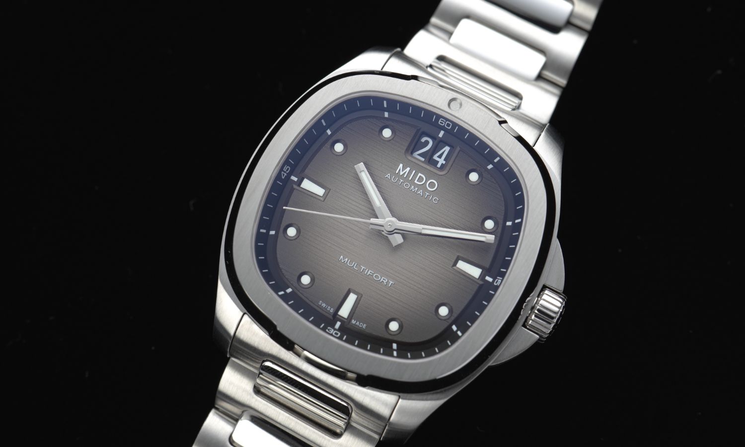 Nahaufnahme des schwarzen Zifferblatts der Mido Multifort TV Big Date Referenz M049.526.11.081.00 am Edelstahlband abgebildet vor schwarzem Hintergrund