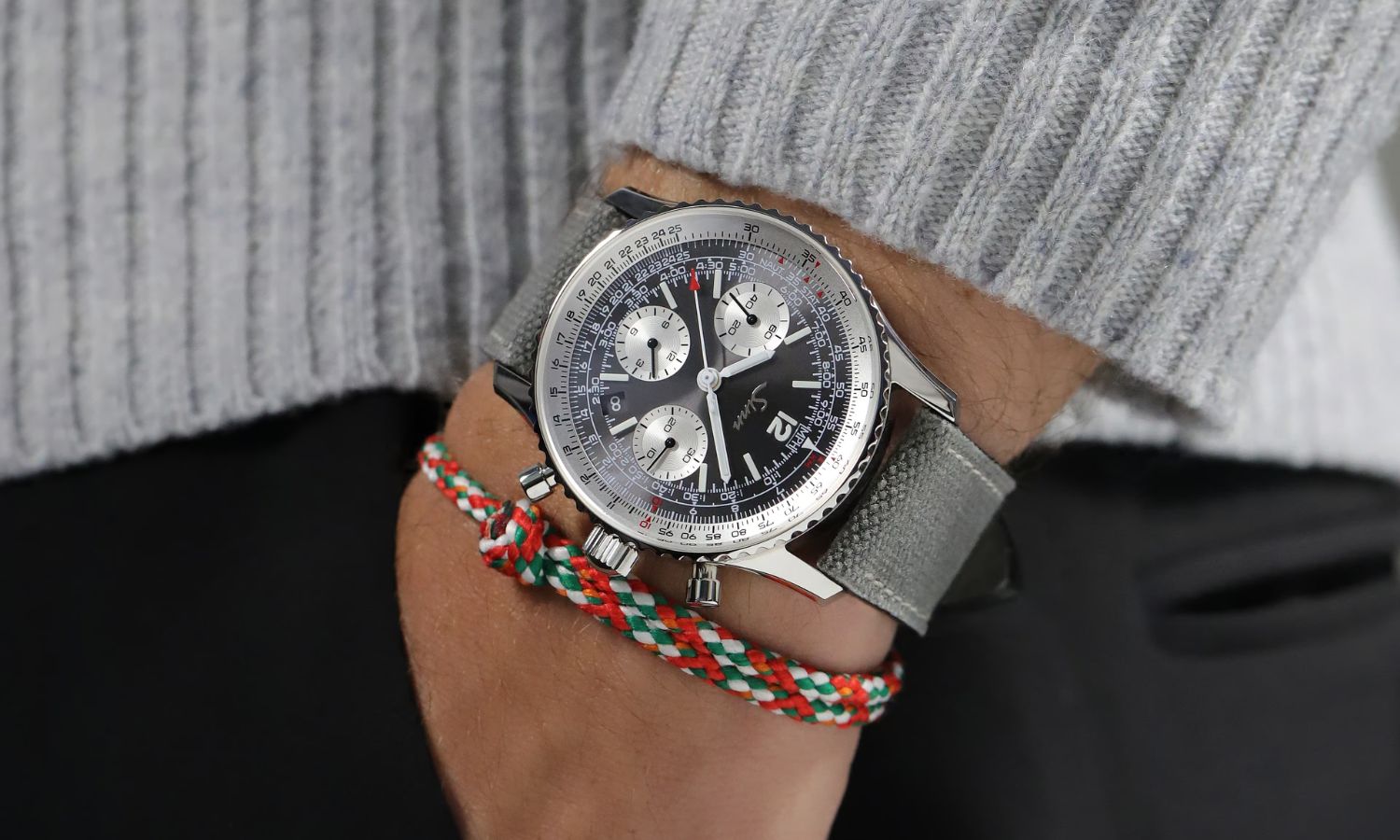 Sinn 903 St II A mit anthrazitfarbenem Zifferblatt am grauen Textilarmband an einem Handgelenk mit grauem Ärmel getragen