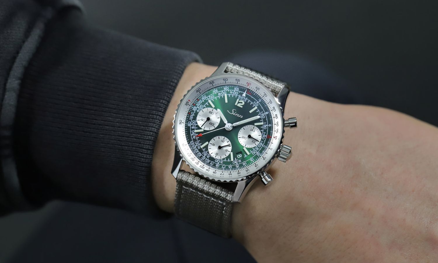 Sinn 903 St II G mit dunkelgrünem Zifferblatt am Textilarmband an einem Handgelenk mit dunkelblauem Ärmel getragen
