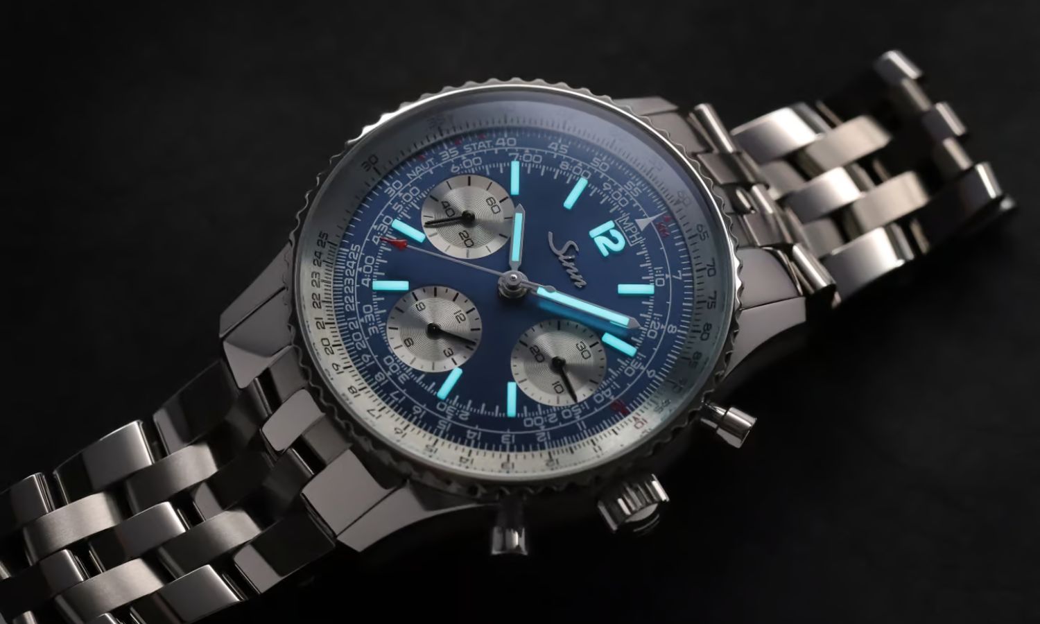 Sinn 903 Ti II Jubiläum mit dunkelblauem Zifferblatt am Edelstahlarmband liegend auf schwarzem Untergrund