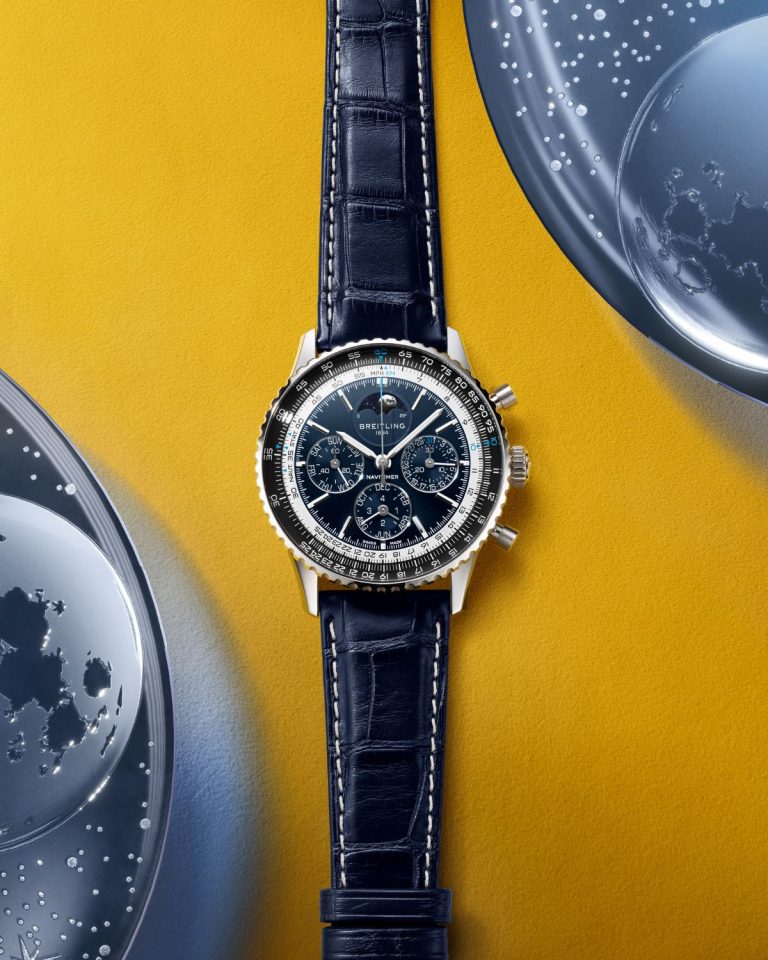 Breitling Navitimer B19 Chronograph 43 Perpetual Calendar mit blauem Zifferblatt am blauen Lederarmband liegend auf gelbem Untergrund