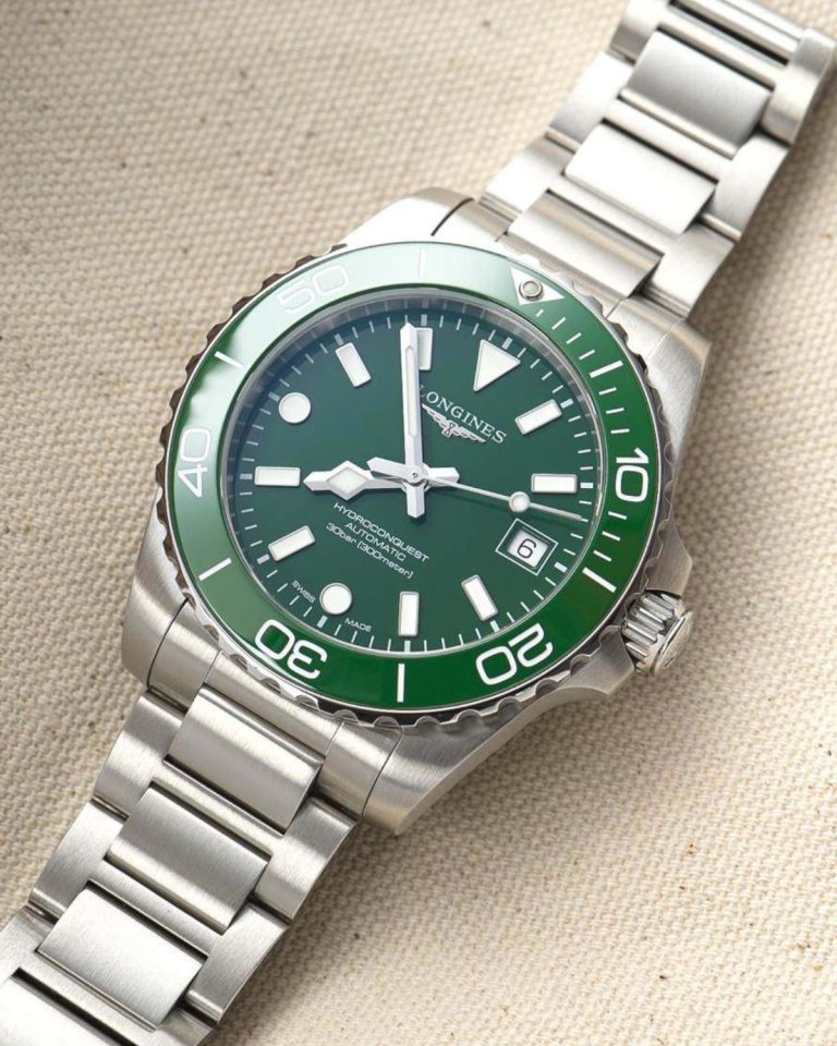 Longines HydroConquest 2026 mit grünem Zifferblatt am Edelstahlarmband liegend auf beigem Untergrund von vorne abgebildet
