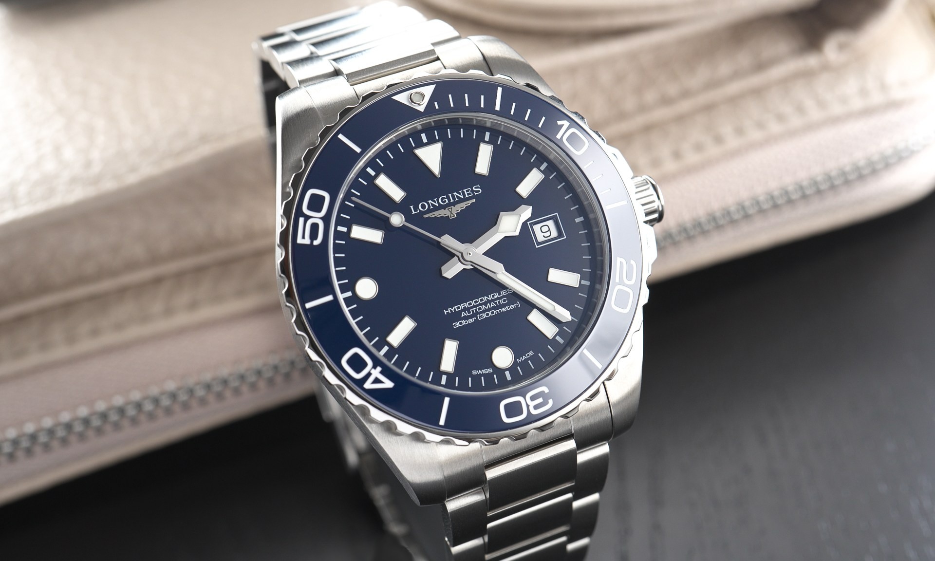 Longines HydroConquest 2026 mit blauem Zifferblatt am Edelstahlarmband stehend vor einem Buch von vorne abgebildet