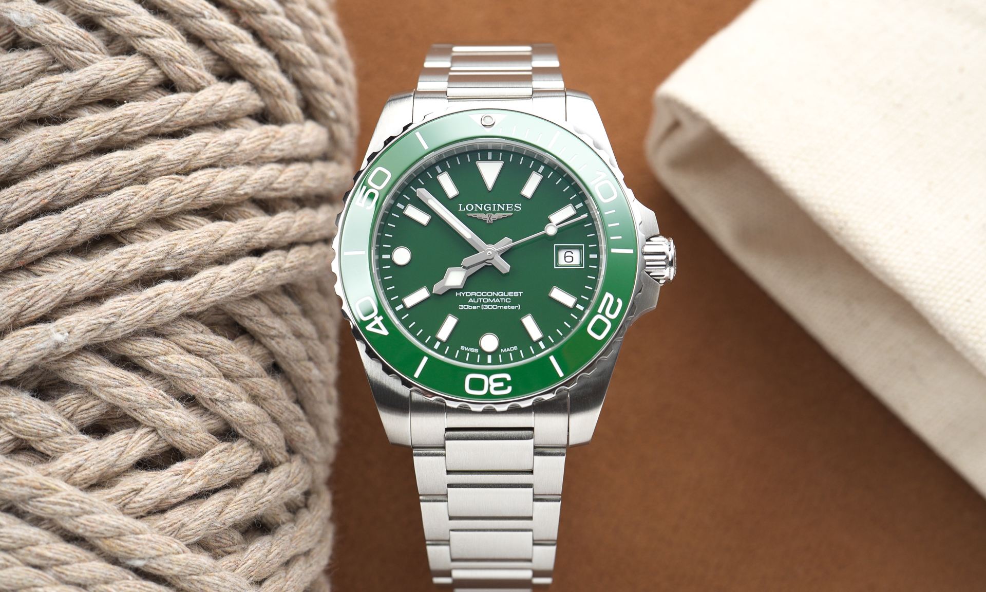 Longines HydroConquest 2026 mit grünem Zifferblatt am Edelstahlarmband stehend vor braunem Hintergrund von vorne abgebildet