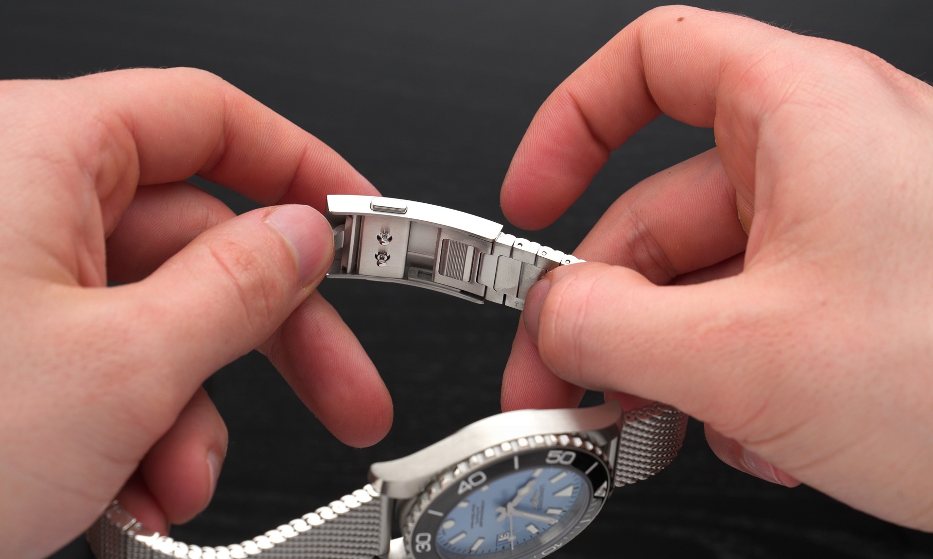 Das Milanaise-Armband der Longines HydroConquest mit Blick auf die Schnellverstellung der Schließe in zwei Händen gehalten