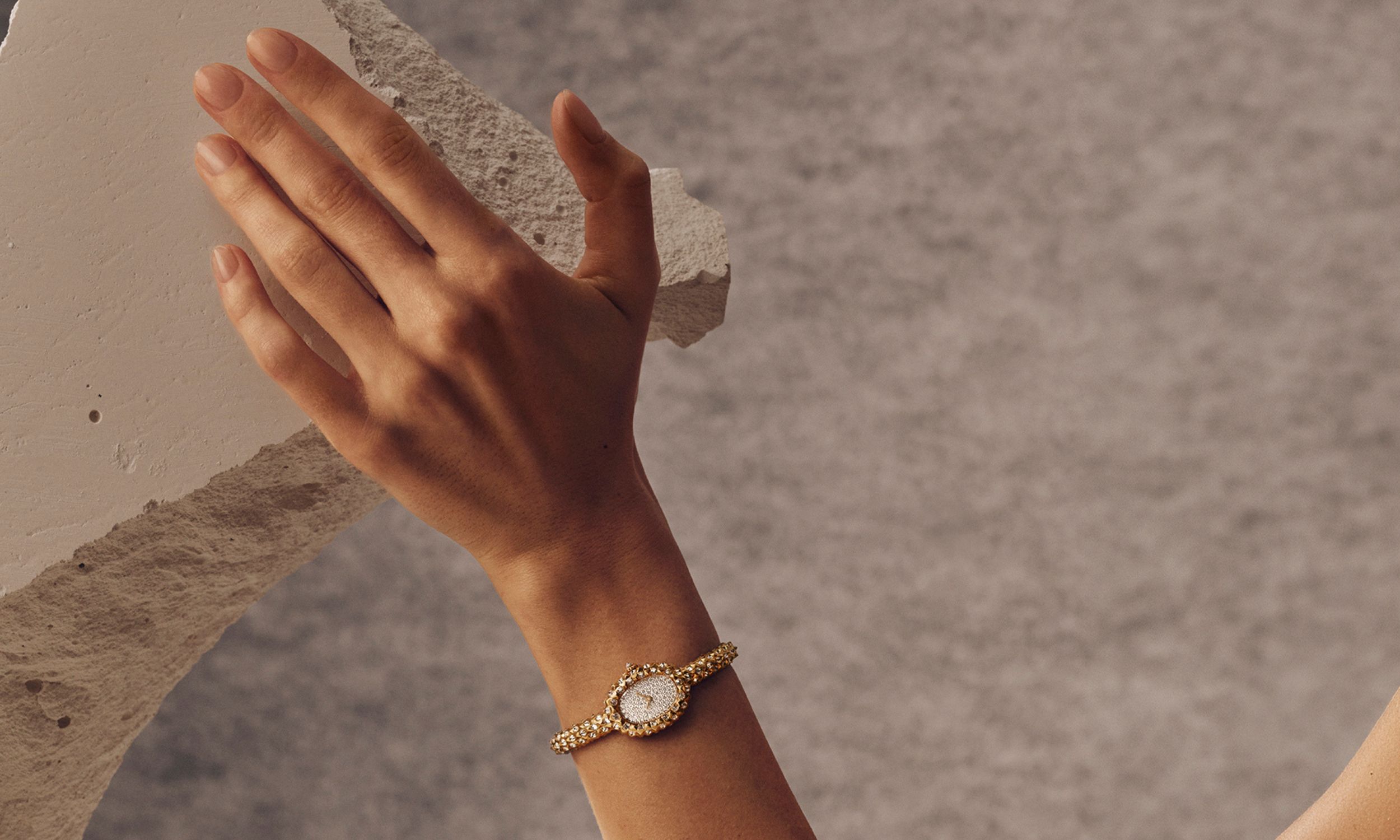 Wristshot einer Cartier Baignoire am Handgelenk. Hand ruht auf Felsen