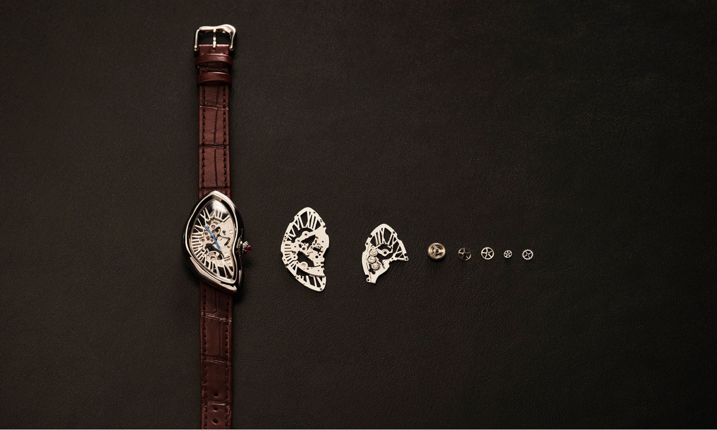 Eine skelletierte Cartier Crash daneben kleiner werdende Werkbauteile