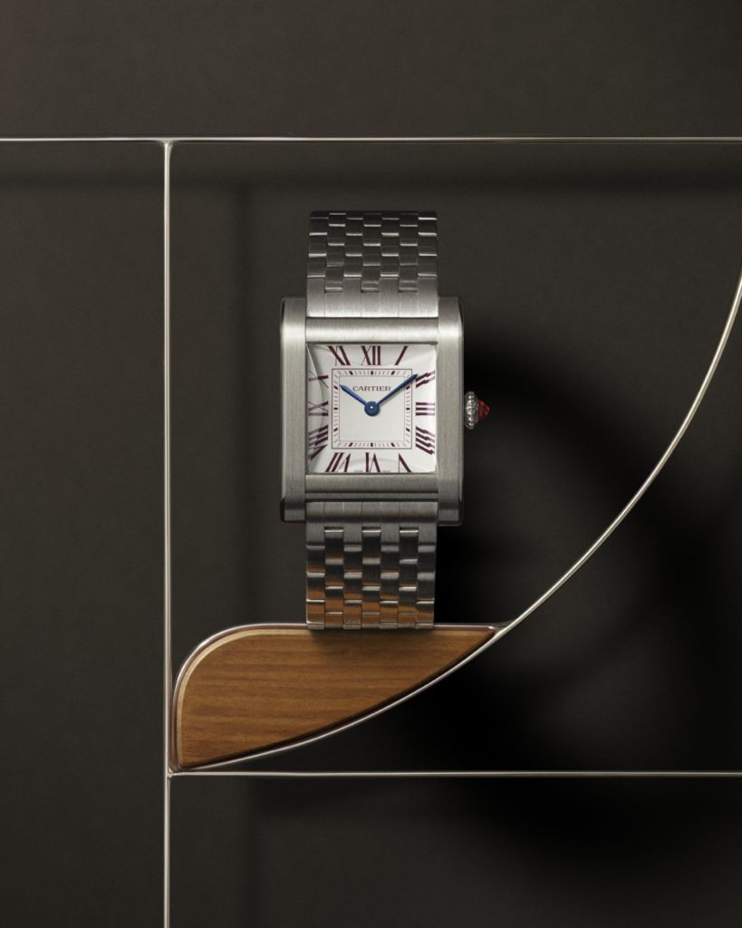 Cartier Tank Normale in der Frontalansicht am Metalarmband vor geometrischem Hintergrund