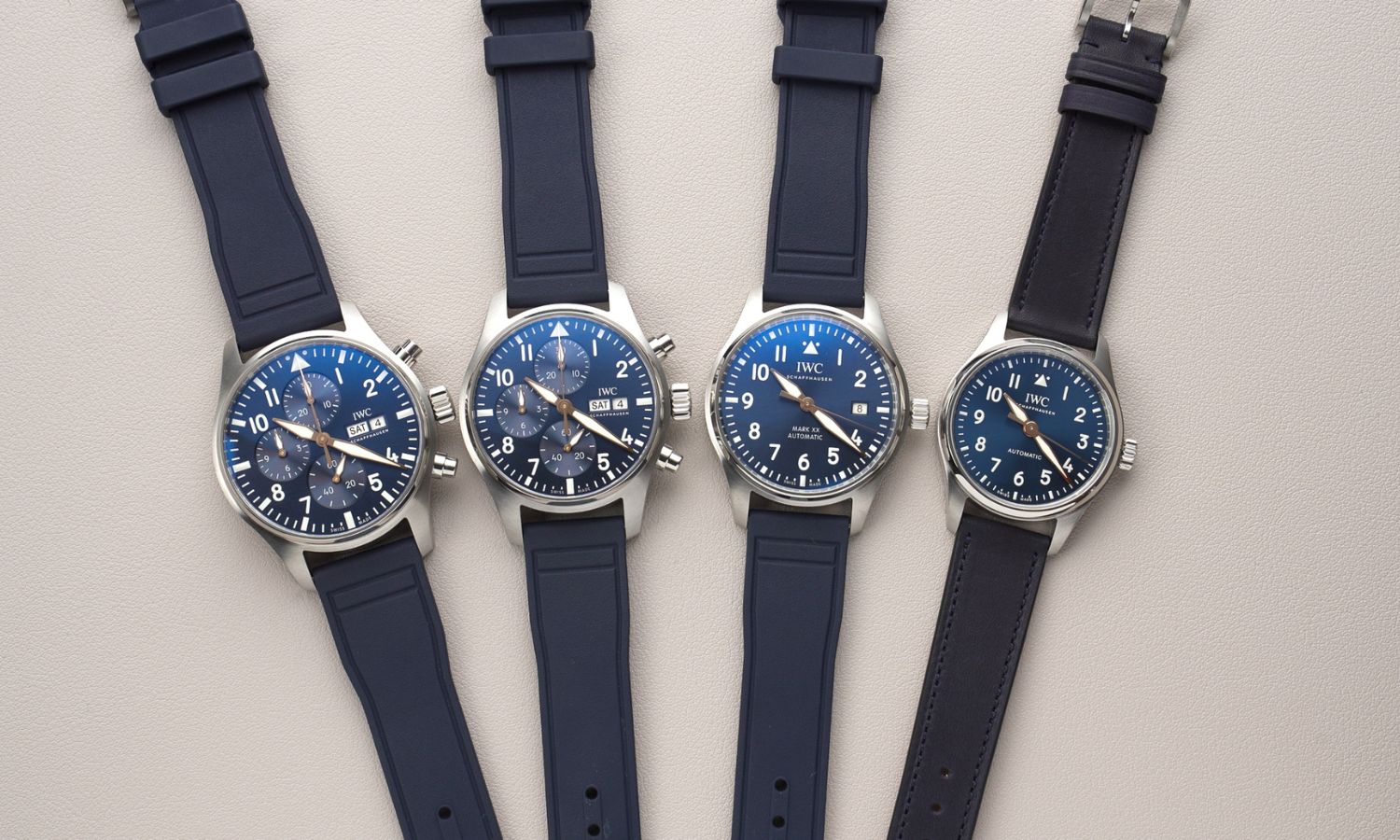 4 Modelle der IWC Le Petit Prince 20 Jahre Jubiläums-Edition nebeneinander liegend auf grauem Untergrund von vorne abgebildet