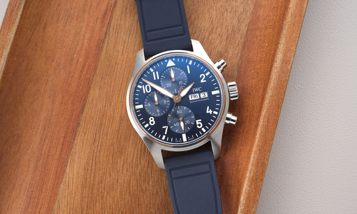 IWC Pilot's Watch Chronograph 41 Le Petit Prince IW388120 mit dunkelblauem Zifferblatt am dunkelblauen Gummiband liegend auf hölzernem Untergrund