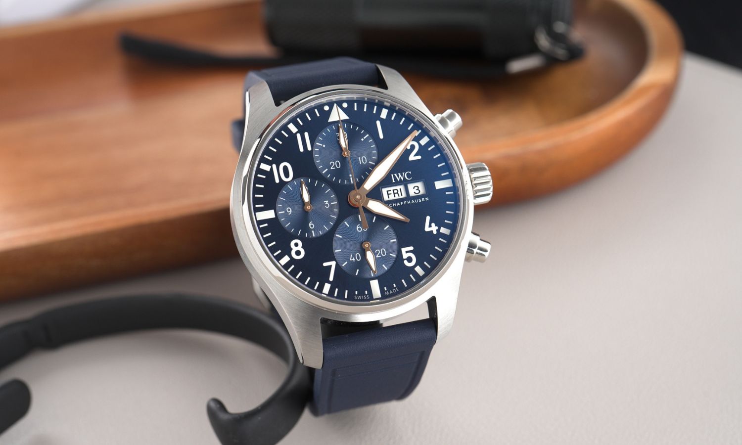 IWC Pilot's Watch Chronograph 41 Le Petit Prince IW388120 mit dunkelblauem Zifferblatt am dunkelblauen Gummiband stehend vor hölzernem Untergrund