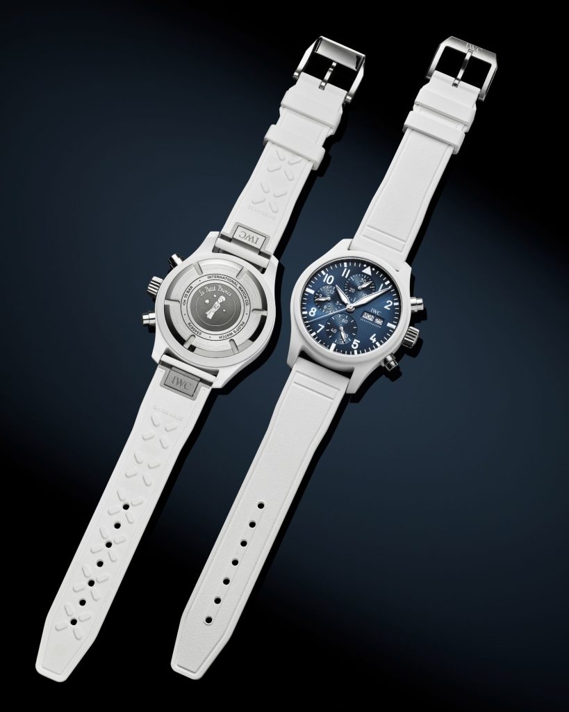 IWC Pilot’s Watch Chronograph 41 Le Petit Prince (White Ceramic) mit dunkelblauem Zifferblatt am weißen Kautschukarmband liegend von vorne und von hinten abgebildet vor dunkelblauem Hintergrund