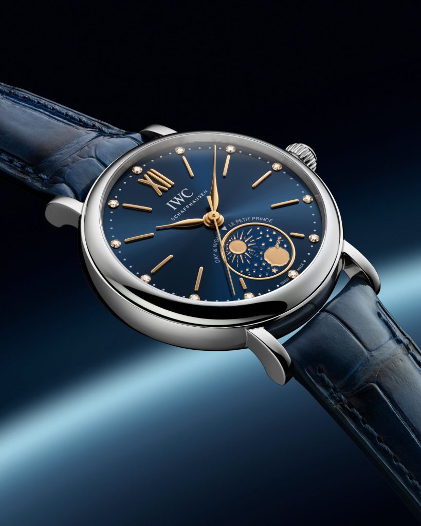 IWC Portofino Automatic Day & Night 34 Le Petit Prince mit dunkelblauem Zifferblatt am dunkelblauen Lederarmband abgebildet vor dunkelblauem Hintergrund