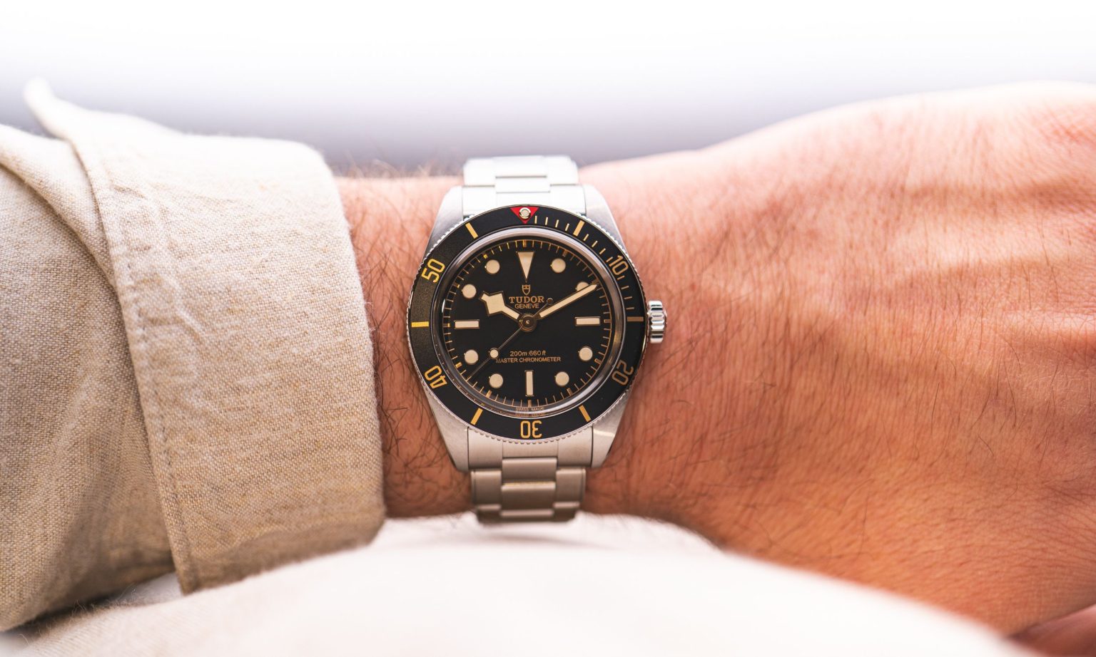 Wristshot der neuen TUDOR Black Bay 58 am Stahlband mit beiger Hemdmanschette